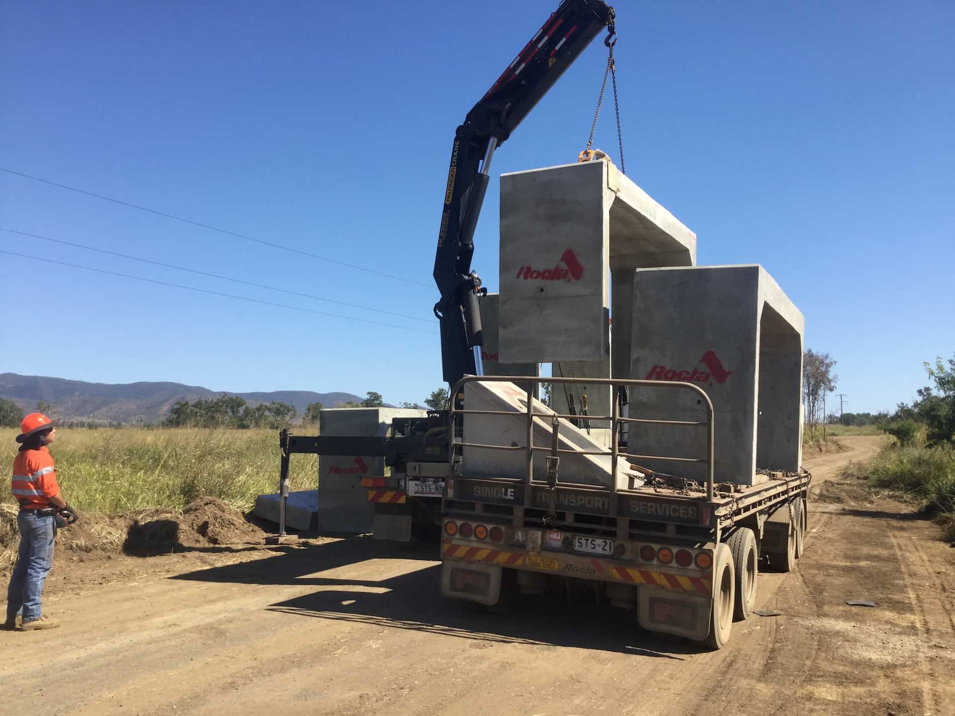 A Man Is Standing Next To A Truck That Is Being Lifted By A Crane — Single Transport Services In Palmyra, QLD
