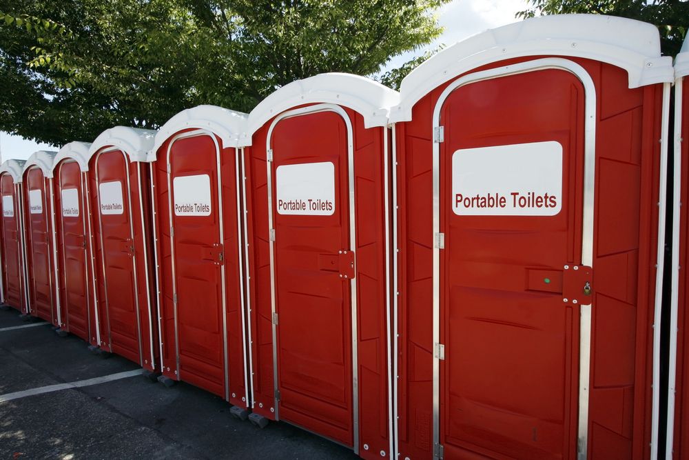 A Row of Red Portable Toilets in a Parking Lot — Bowen Hire & Sales in Airlie Beach, QLD