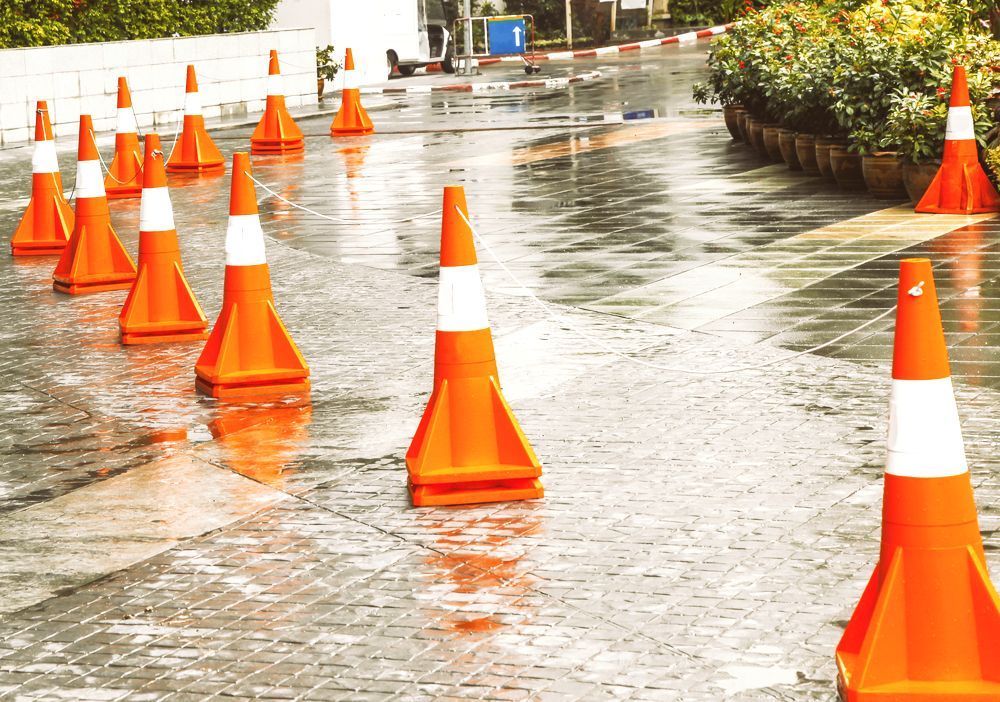 A Row of Orange and White Traffic Cones on a Wet Street — Bowen Hire & Sales in Bowen, QLD