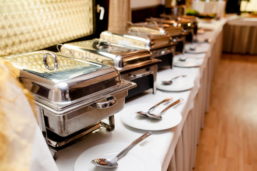 A Buffet Line With Plates and Utensils on a Table — Bowen Hire & Sales in Bowen, QLD