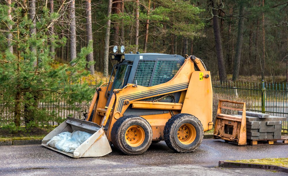 A Small Bulldozer is Parked on the Side of the Road in Front of a Forest — Bowen Hire & Sales in Bowen, QLD