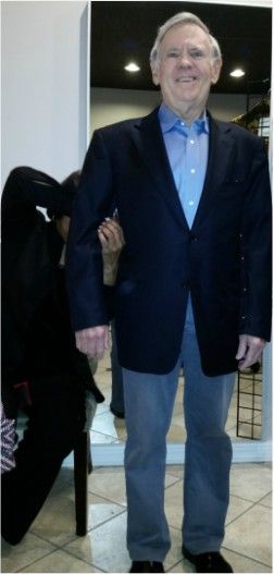 A man in a suit is standing in front of a mirror