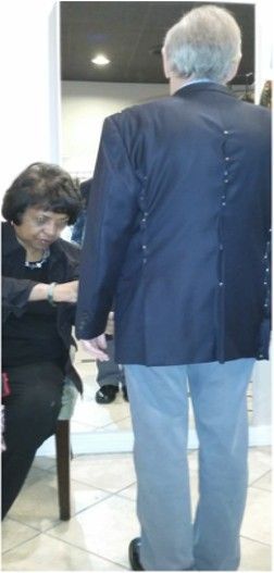A man in a suit is standing next to a woman in a chair