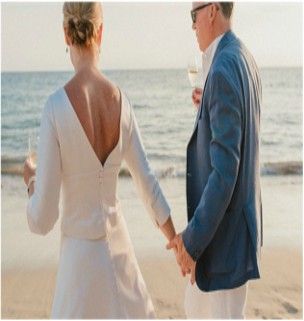 A bride and groom are holding hands on the beach.