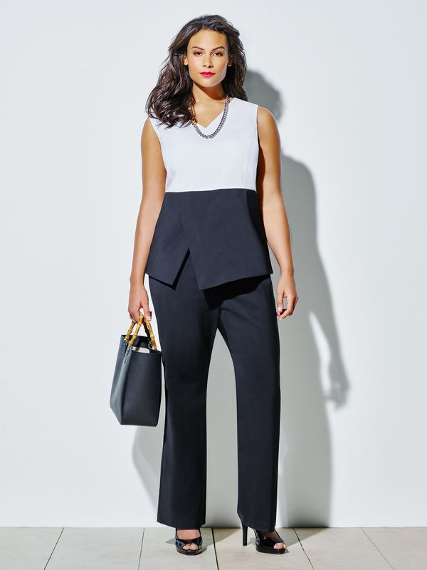 A woman is wearing a black and white suit and holding a black bag.