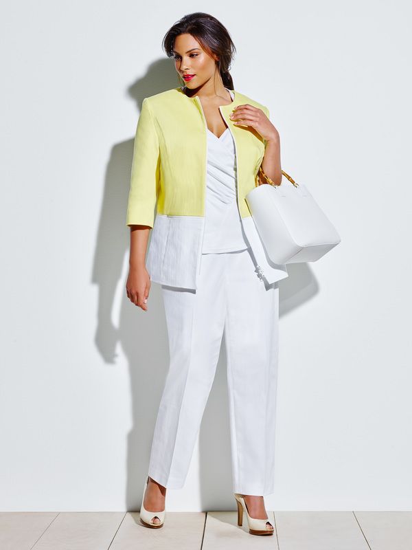 A woman wearing a yellow jacket and white pants is holding a white bag.