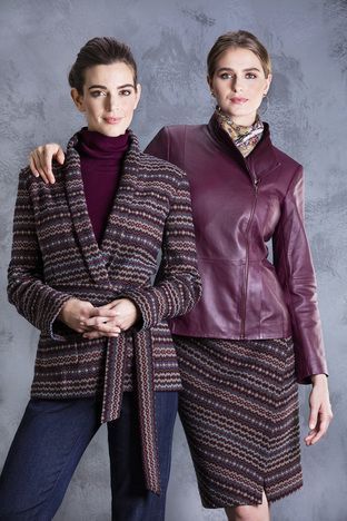 Two women are standing next to each other wearing jackets and skirts.