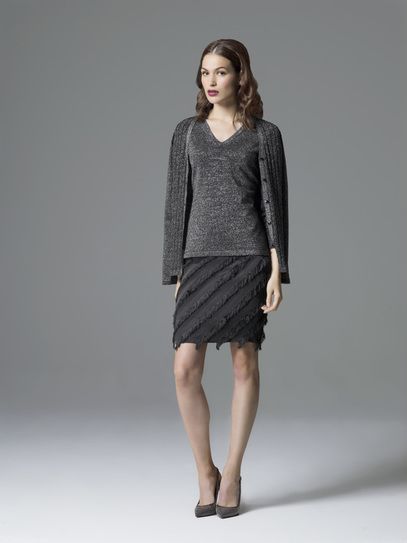 A woman is wearing a sweater and a skirt.