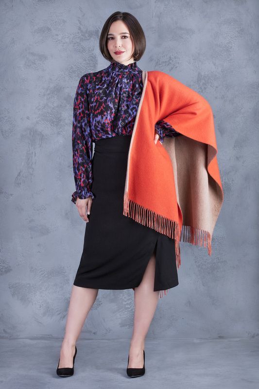 A woman is wearing a black skirt and an orange scarf.