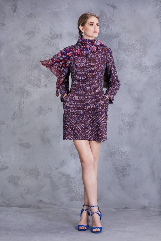 A woman is wearing a purple dress and a scarf around her neck.