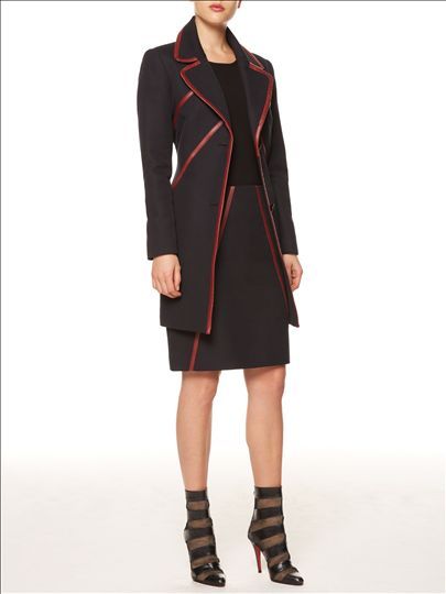 A woman is wearing a black coat and a black skirt