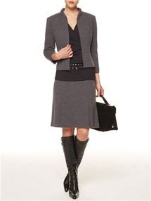 A woman is wearing a gray suit and black boots
