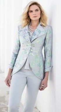 A woman is wearing a suit and standing next to a wall.
