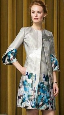 A woman is wearing a silver coat and a blue dress.