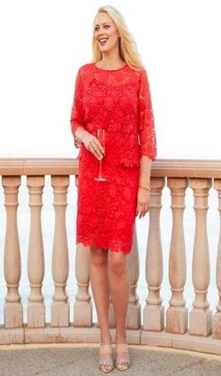 A woman in a red lace dress is holding a glass of wine.