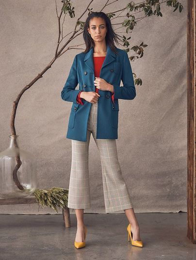 A woman is wearing a blue jacket and white pants
