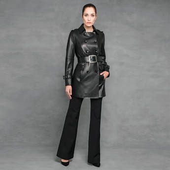 A woman is wearing a black leather trench coat and black pants.
