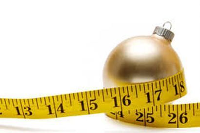 A measuring tape is wrapped around a christmas ornament.