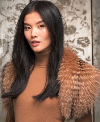 A woman wearing a brown sweater and a fur collar.