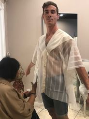 A man is standing next to a woman in a room wearing a white shirt.