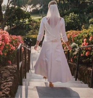 A bride in a white dress and veil is walking down stairs.