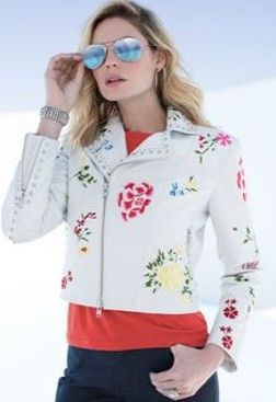 A woman wearing sunglasses and a white jacket with flowers on it.