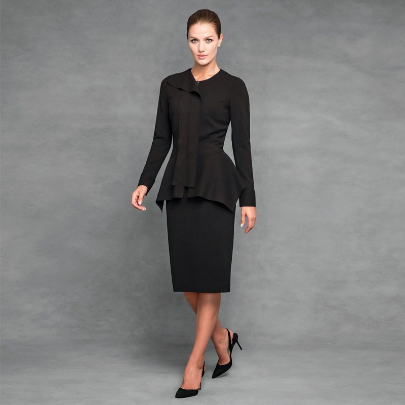 A woman is wearing a black suit and heels
