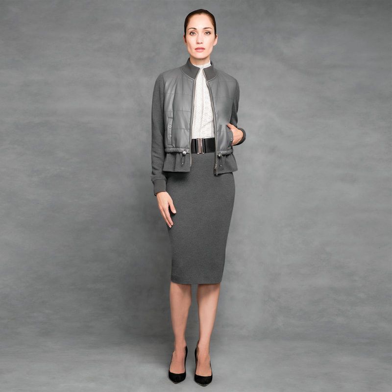A woman wearing a grey jacket and a grey skirt