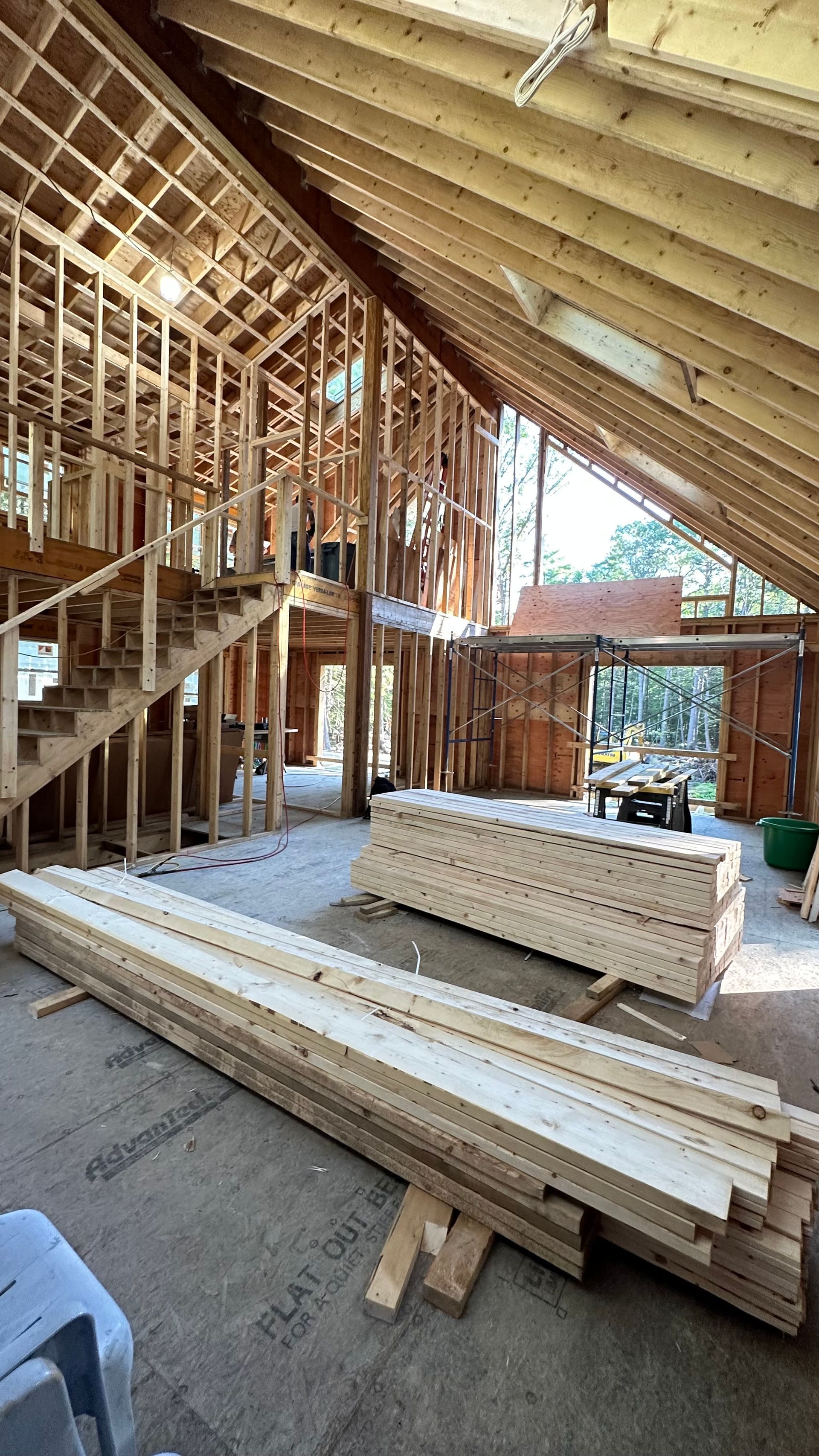 A stack of wood is sitting on the floor in a room under construction.