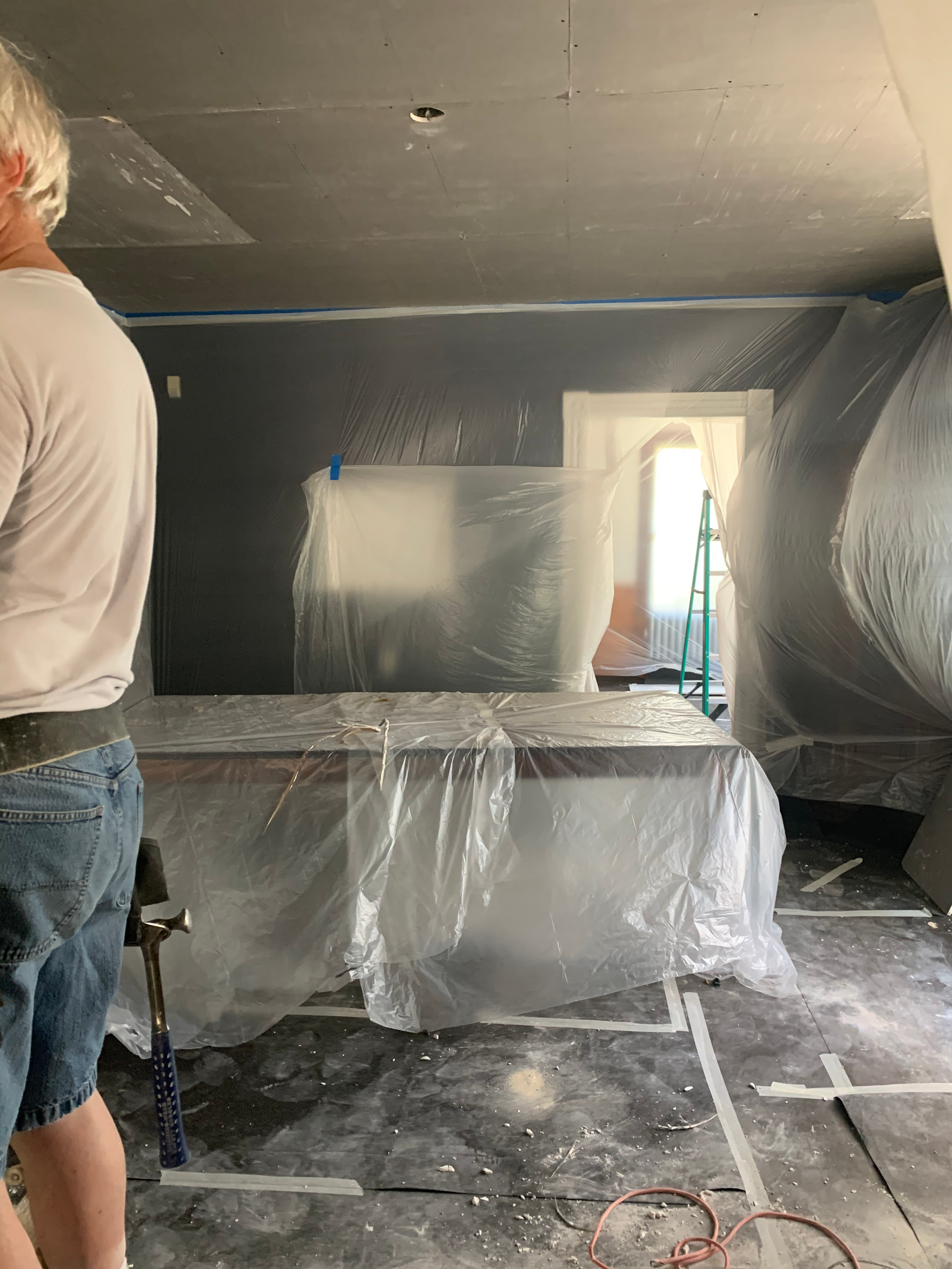 A man is standing in a room covered in plastic.