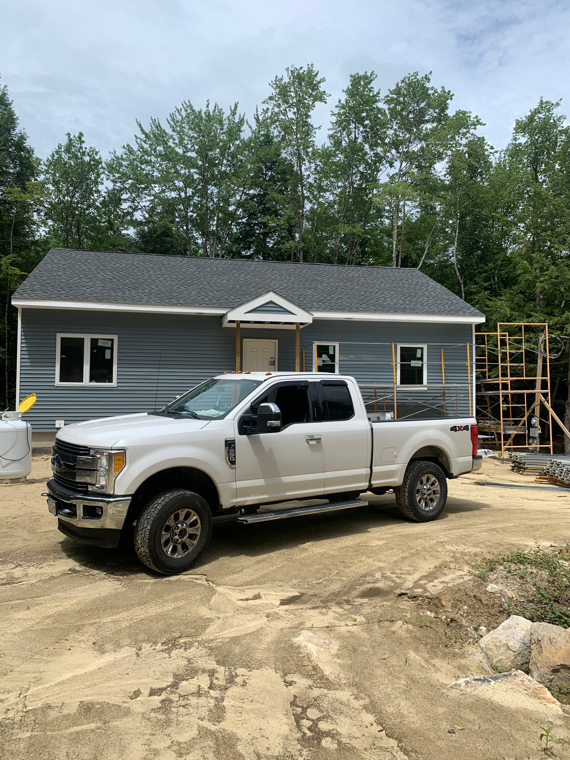 A white truck is parked in front of a house under construction.