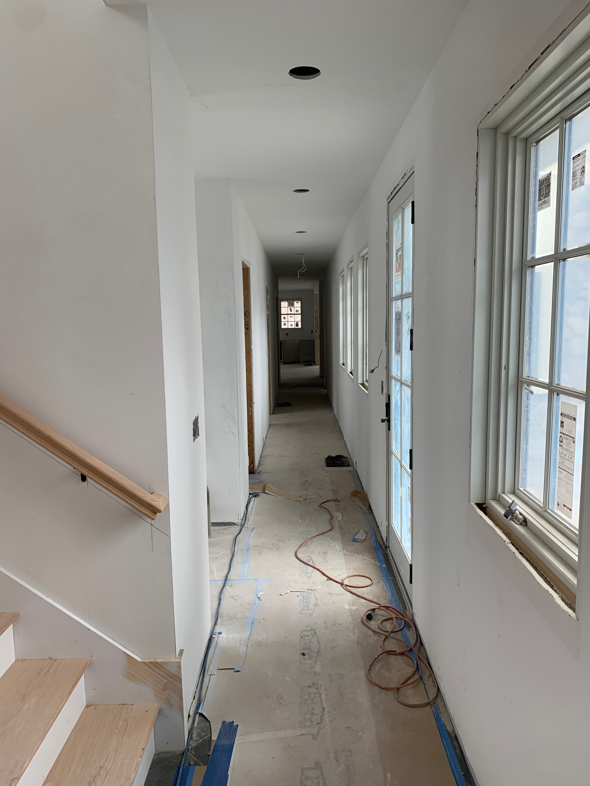 A long hallway with stairs and windows in a house under construction.