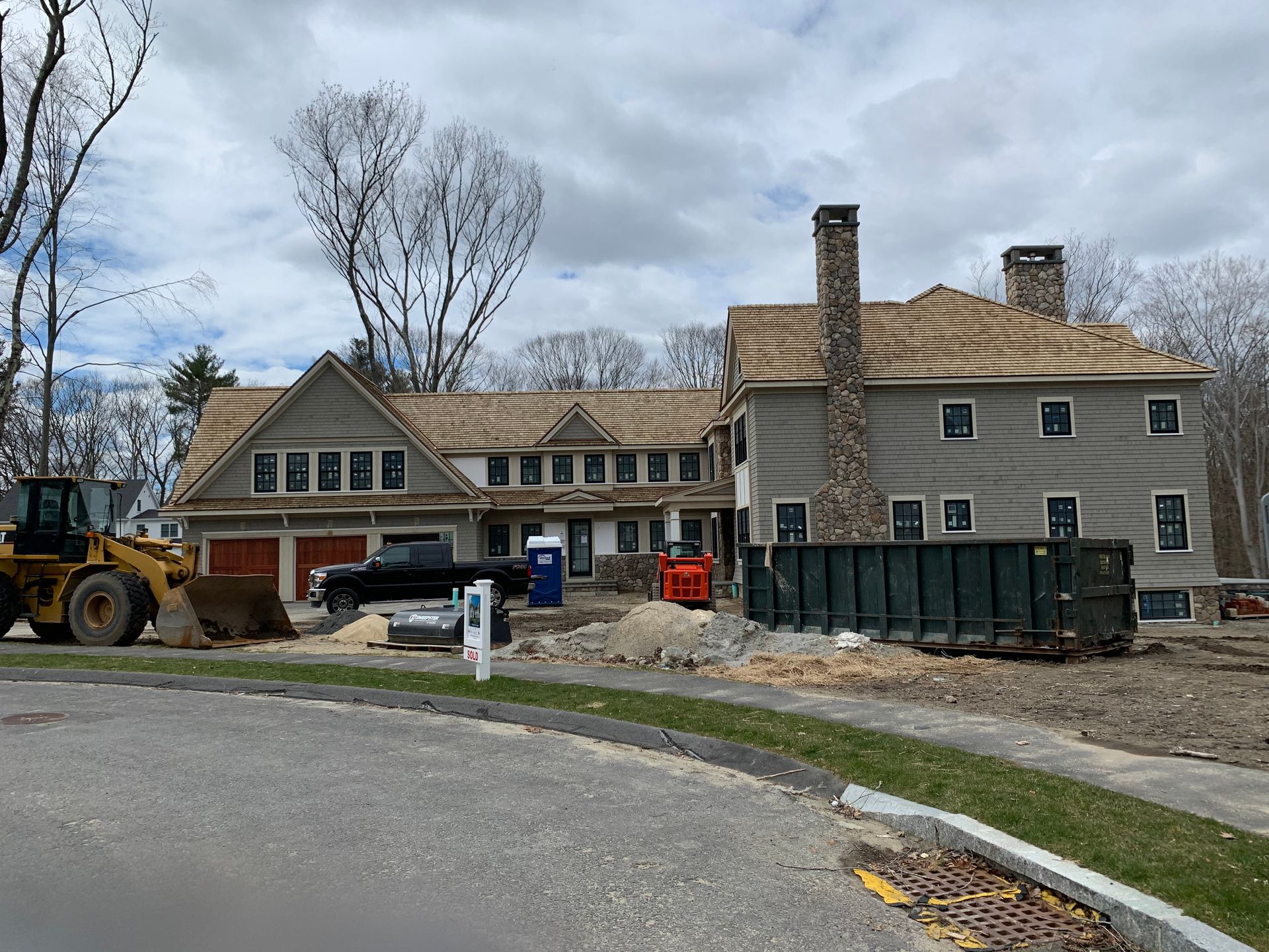 A large house is being built with a dumpster in front of it.