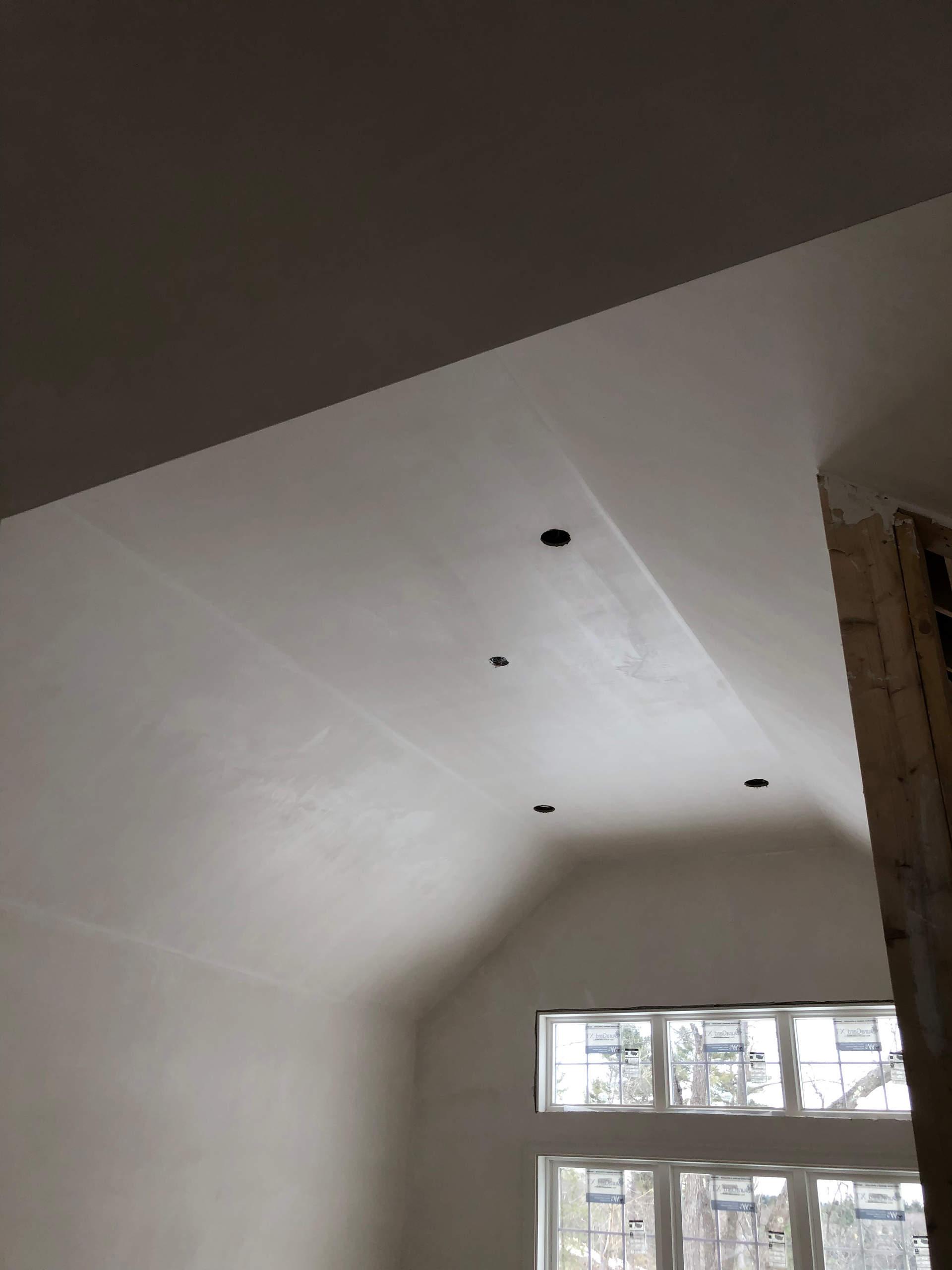 A room with a vaulted ceiling and a lot of windows