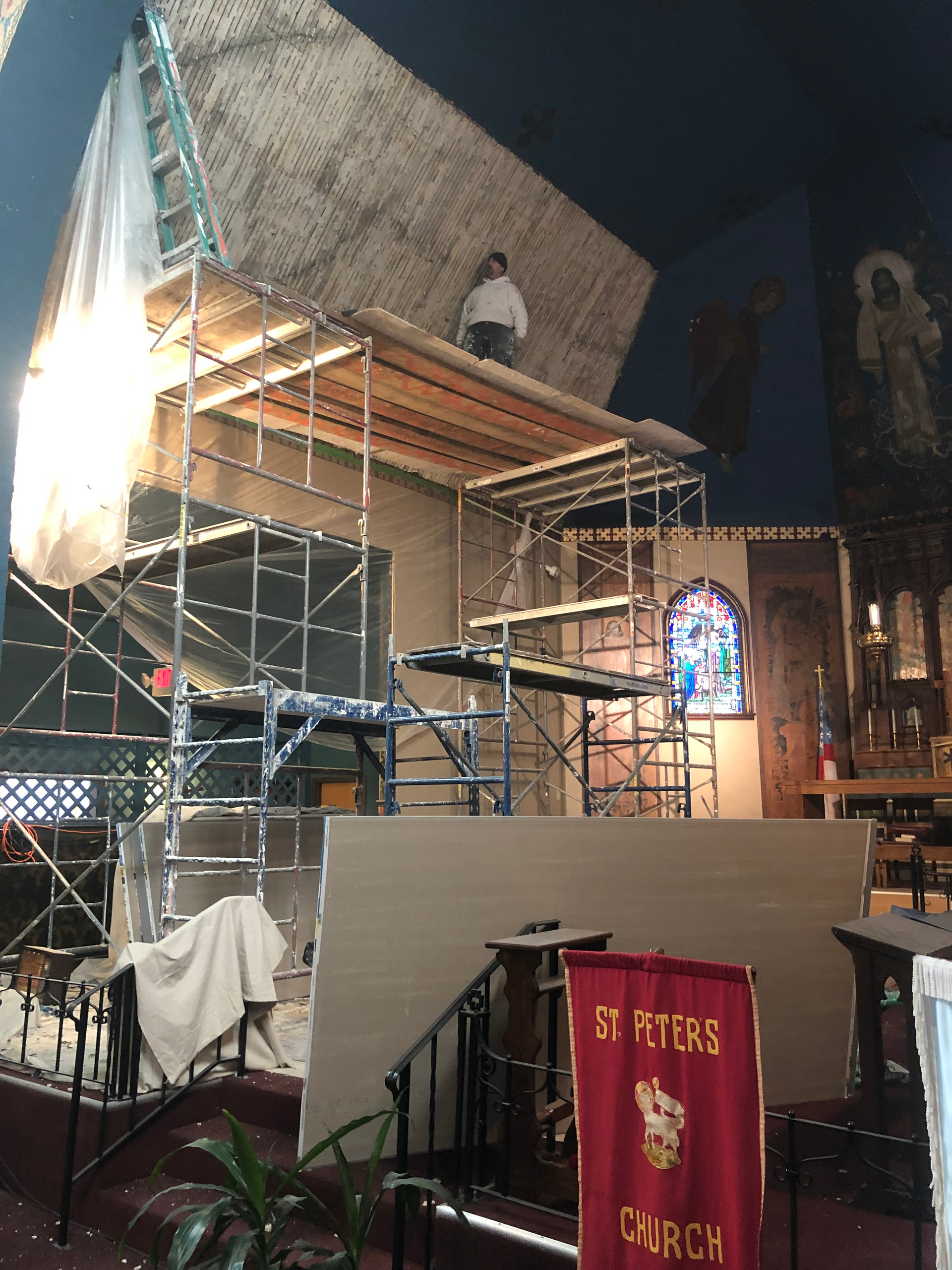 A man is standing on top of a scaffolding in a church.