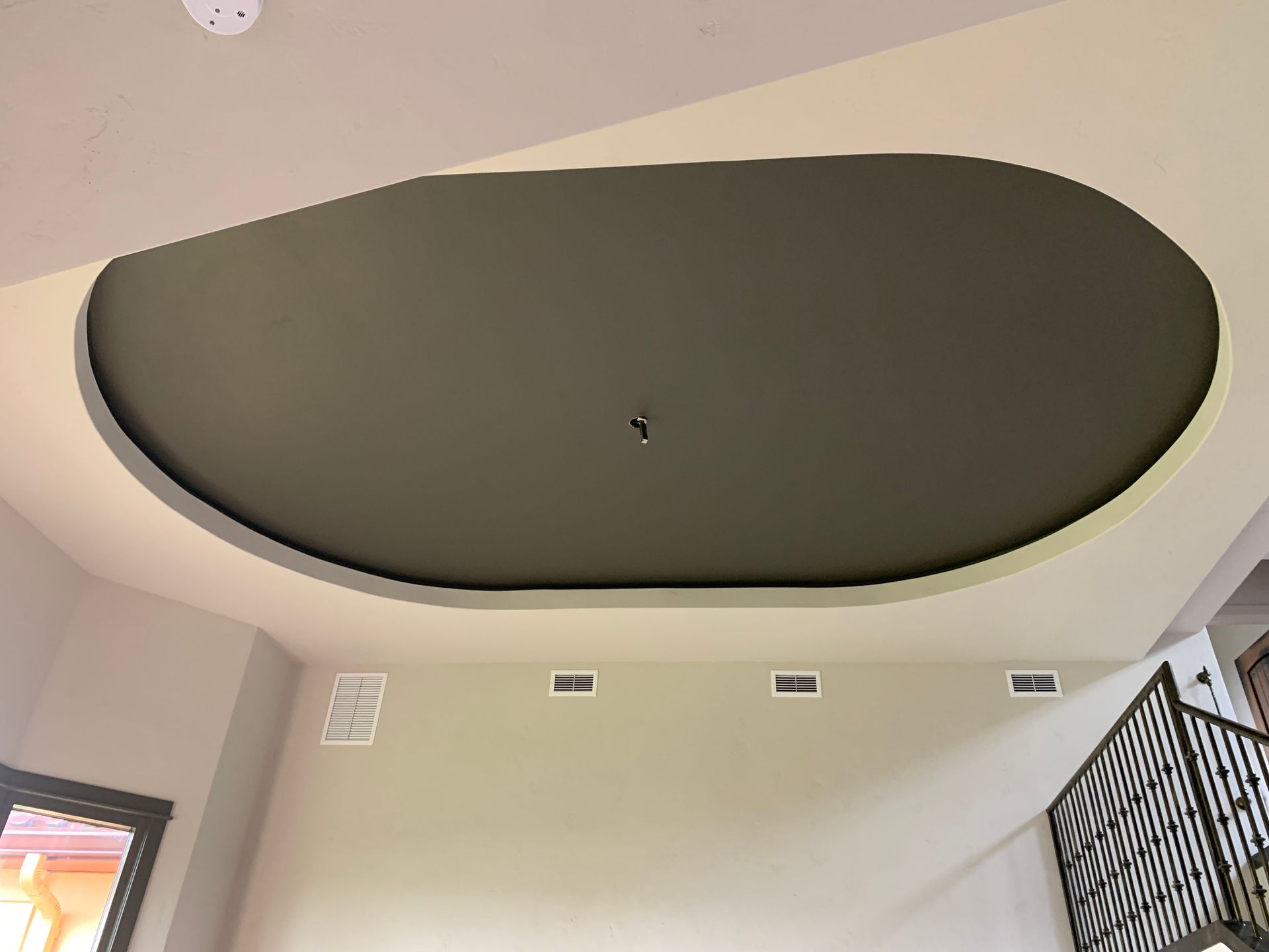 A ceiling in a room with a staircase in the background