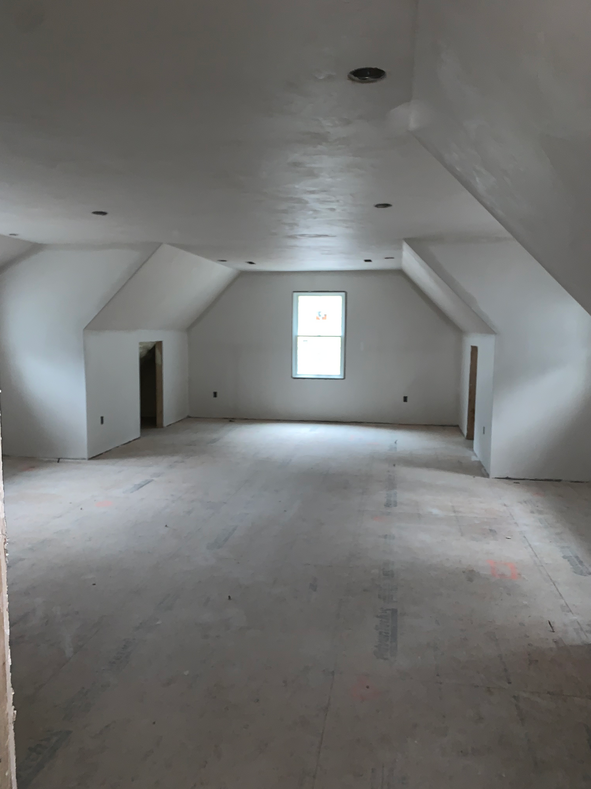 A large empty room with a window in the corner.