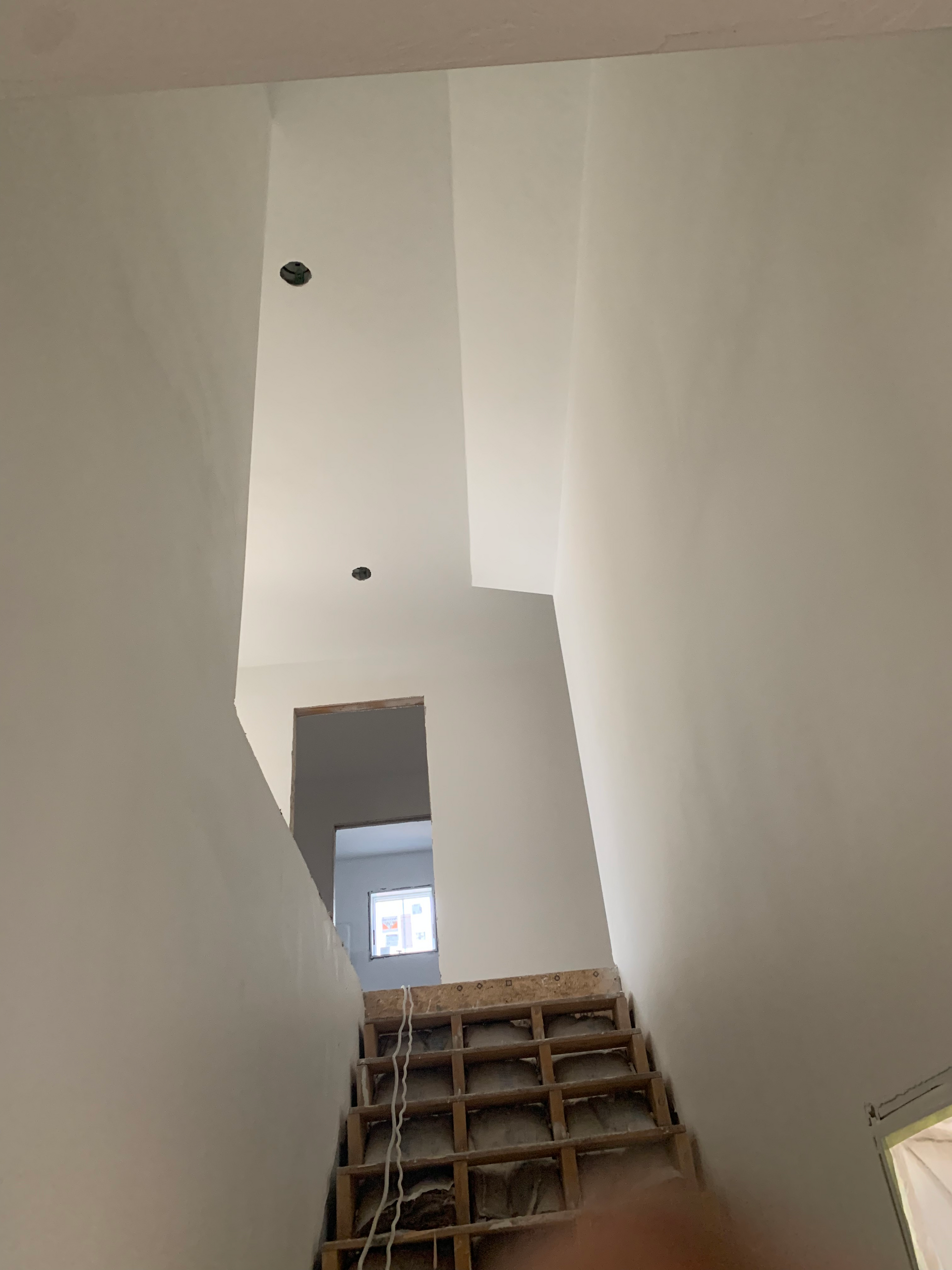 A person is looking up at a staircase in a building under construction.