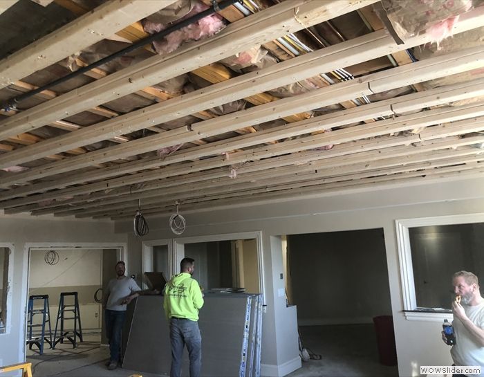 A man in a green shirt is standing in a room under construction.