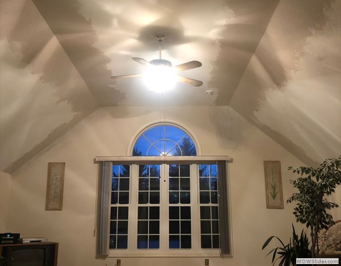 A living room with a ceiling fan and a large window.