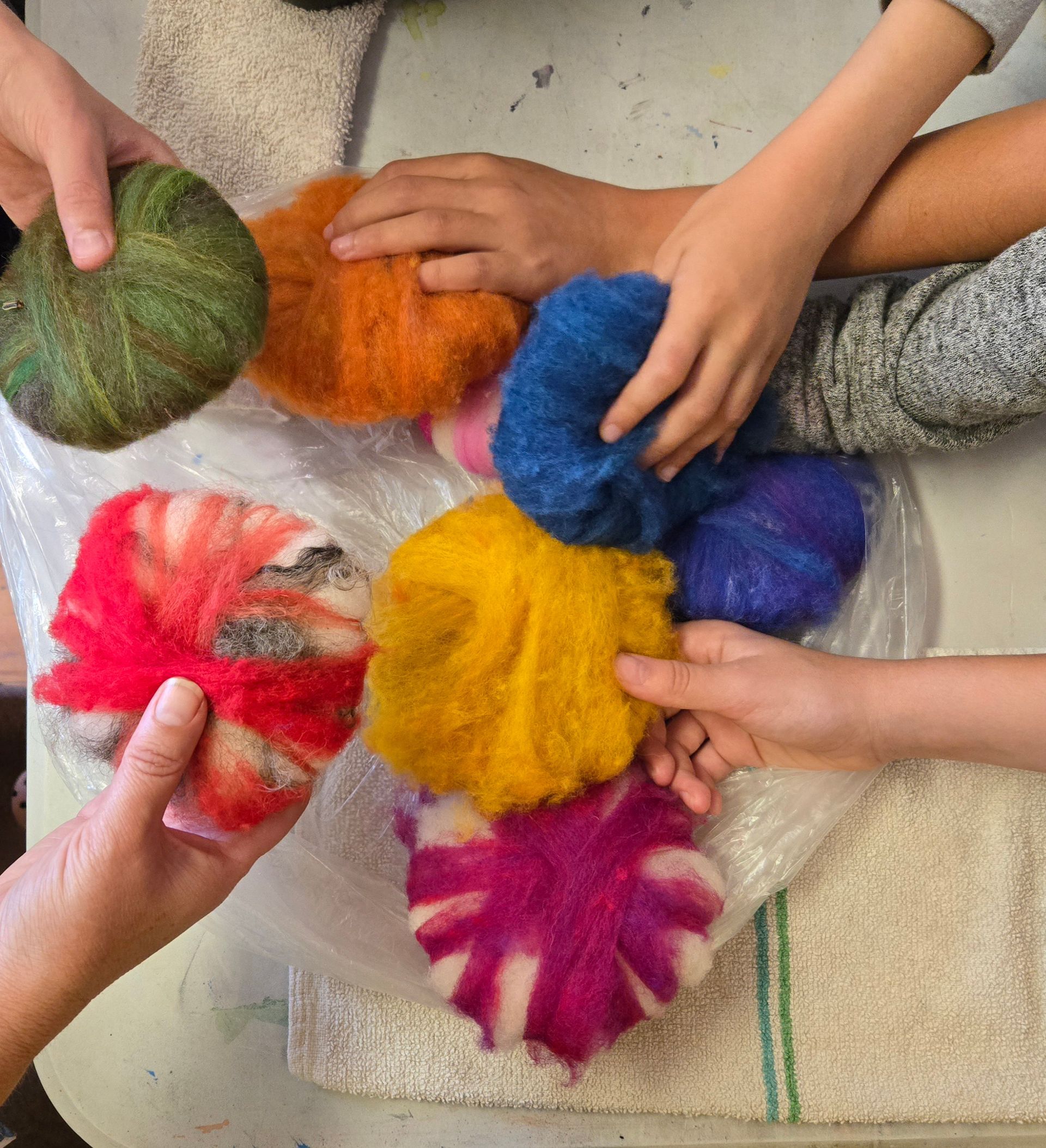 Hands holding colorful felted wool balls.