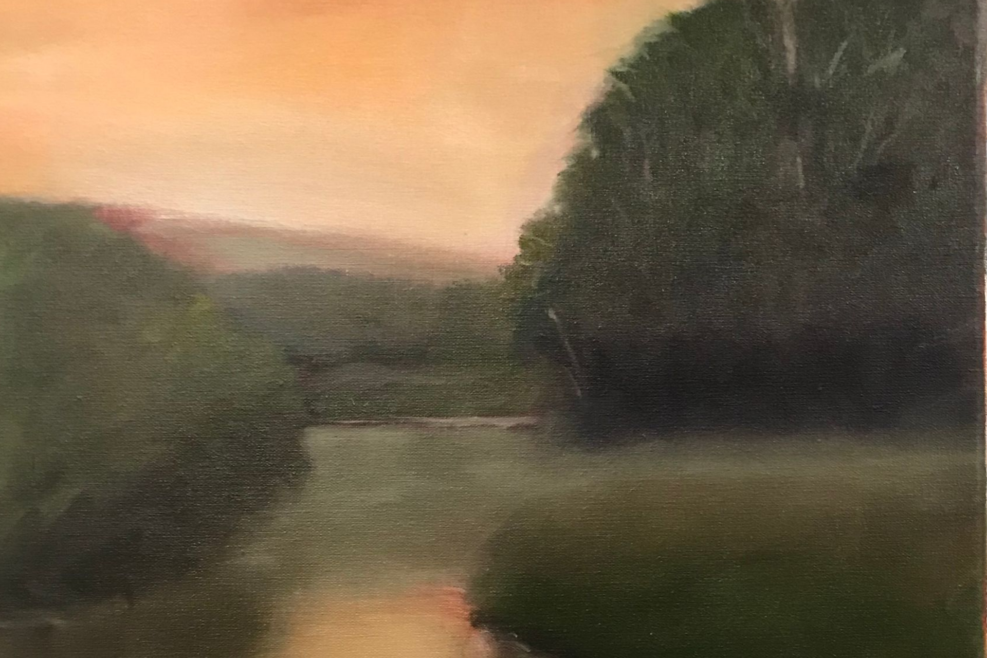 River scene with green foliage, reflecting an orange sunset in the water.