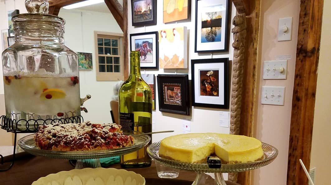 Drinks and desserts at a party: a large water dispenser, pies, and framed art on the wall.