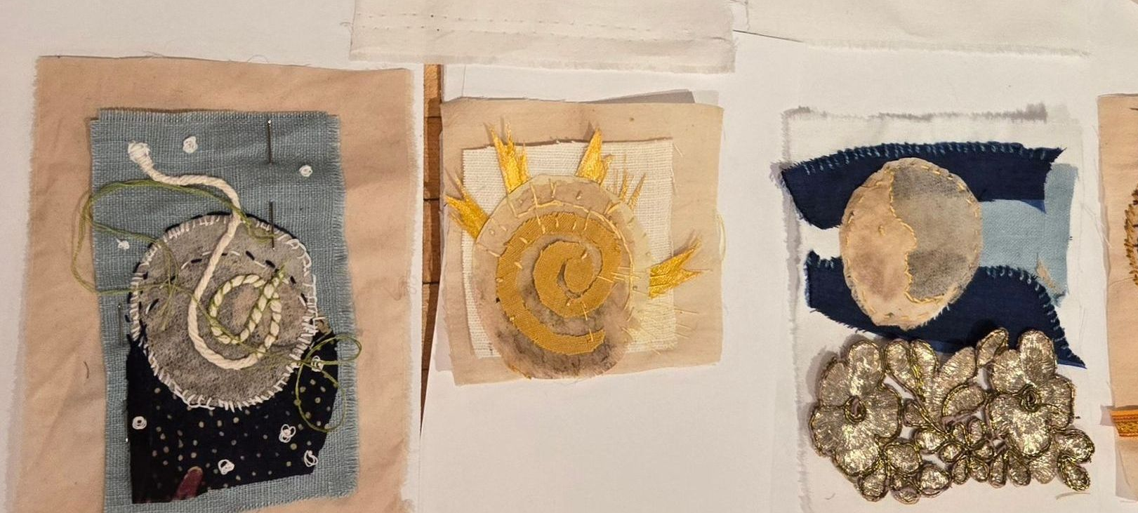 Textile art: Mixed media stitched collages with celestial themes on beige fabric; various colors and textures.