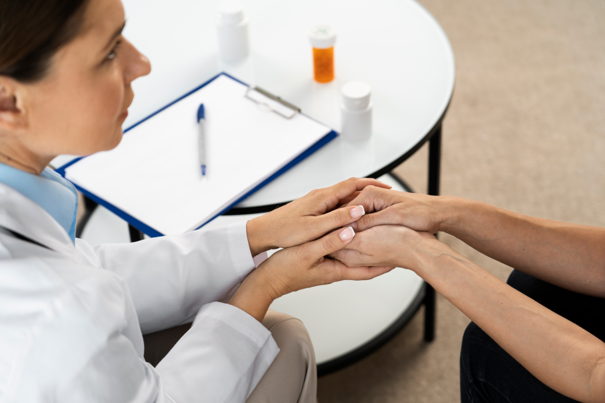 A healthcare professional talking to a patient while holding her hands