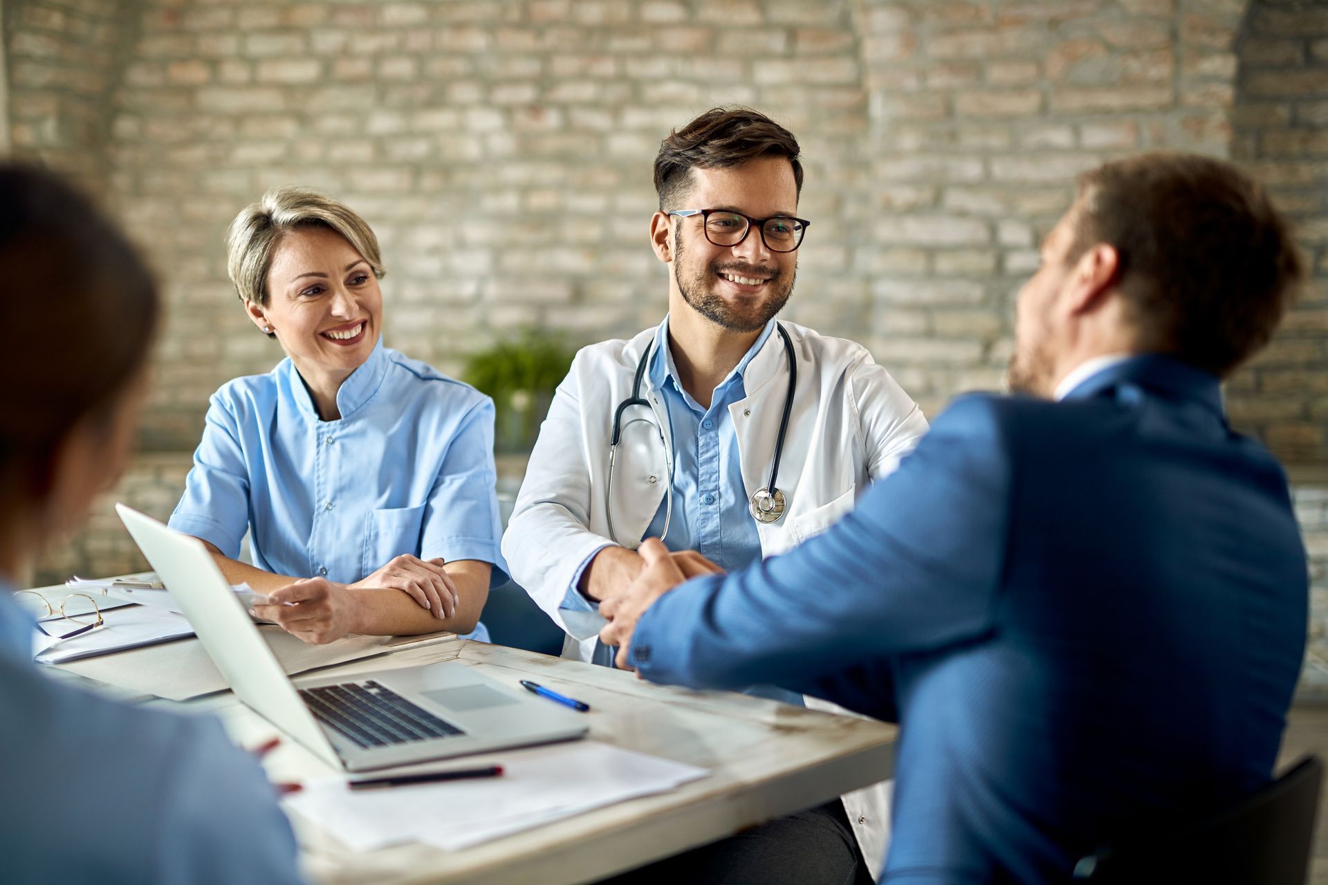 A group of doctors and nurses are having a meeting with a man in a suit.