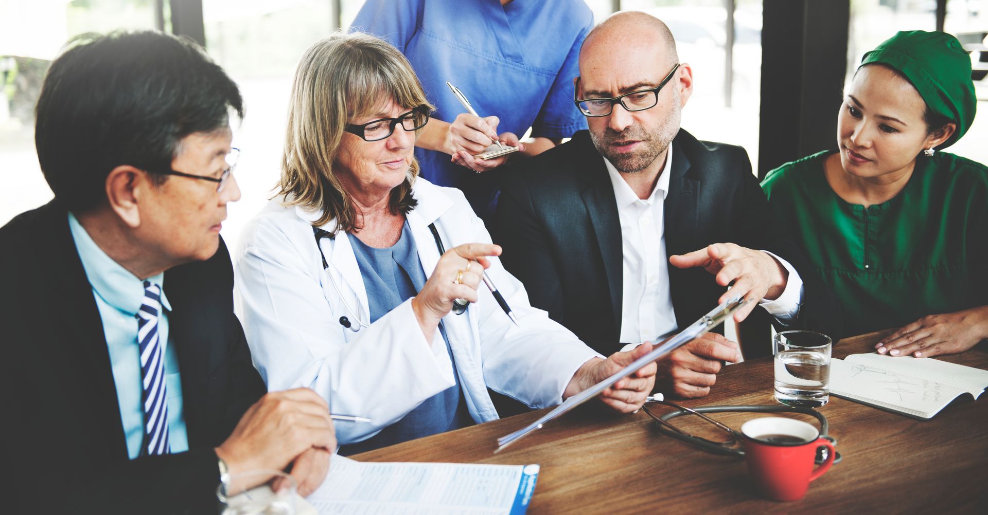 A group of doctors and nurses are having a meeting at a table.