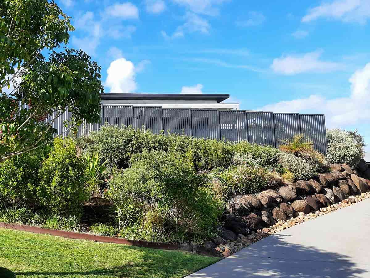 A Large House is Sitting on Top of a Hill Surrounded by Trees and Bushes — Full Circle Landscaping in Tweed Heads, NSW