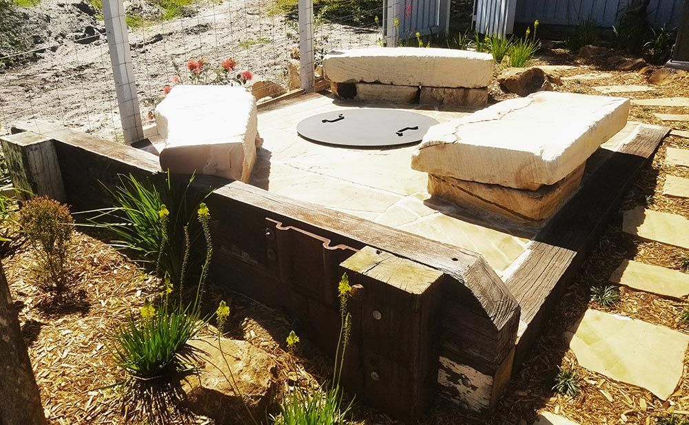 A Stone Patio With A Fire Pit In The Middle Of It — Full Circle Landscaping in Uki, NSW