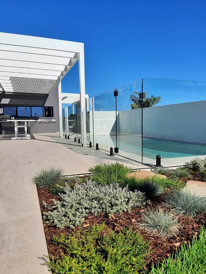A Swimming Pool With a Glass Fence Around It — Full Circle Landscaping in Alstonville, NSW